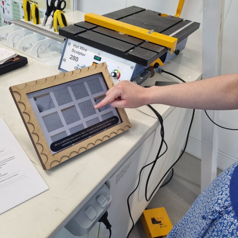 Photo of an iPad that is encased in an artwork portrait cover that shows photos of past artworks done.