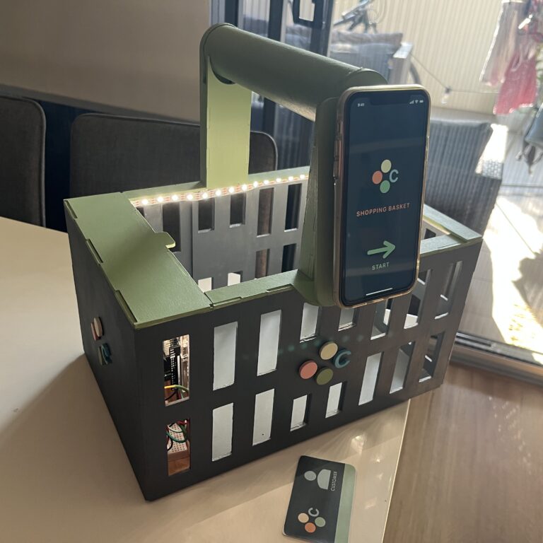 A close up of the CORE Basket, showing the user ID card, and the phone app that connects to the basket