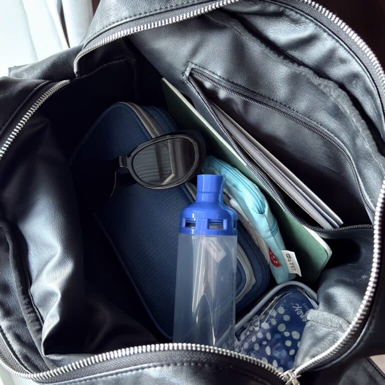 An asthma spacer in a black bag with other random items surrounding it.