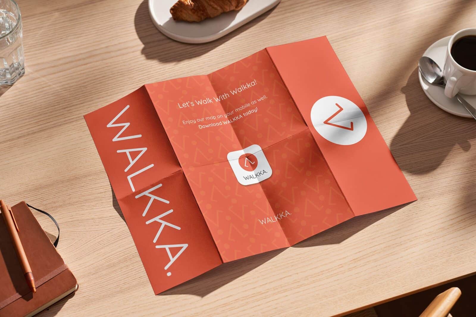 Backside of a WALKKA map placed on a table, displaying the brand’s identity and app download information.